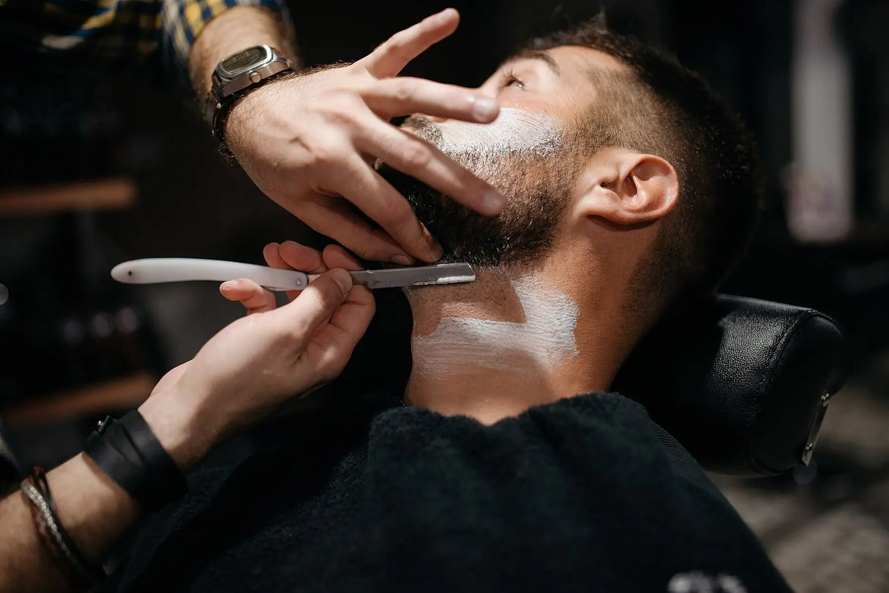 Straight razor along a lathered jawline
